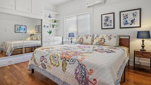 A bedroom with a large bed, a dresser, a mirror, a window with blinds, and two framed pictures on the wall. - Light & Bright Spanish-Style Beauty, 3 min to Zoo! (San Diego)
