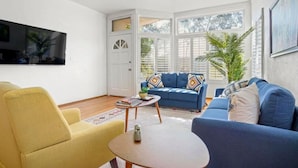 A living room with a yellow armchair, a blue sofa, and a coffee table. - Light & Bright Spanish-Style Beauty, 3 min to Zoo! (San Diego)
