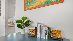 A room with a blue table, a potted plant, decorative elephant figurines, and a framed painting on the wall. - Light & Bright Spanish-Style Beauty, 3 min to Zoo! (San Diego)
