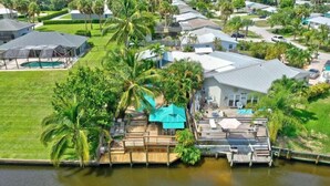 A residential property with a dock, a swimming pool, and a large house with a covered patio.