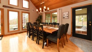 Un espace repas avec une table et des chaises en bois, de grandes fenêtres et un ventilateur de plafond.