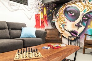 A living room with a chessboard, a sofa, a coffee table, and a wall mural.