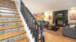 A staircase with colorful tiles, a sofa, a TV, and a fireplace.