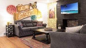 A living room with a sofa, coffee table, and a TV mounted on a brick wall.
