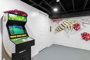 A gaming arcade with a 3D golf game, a wall mural of dice and a hand, and a door.
