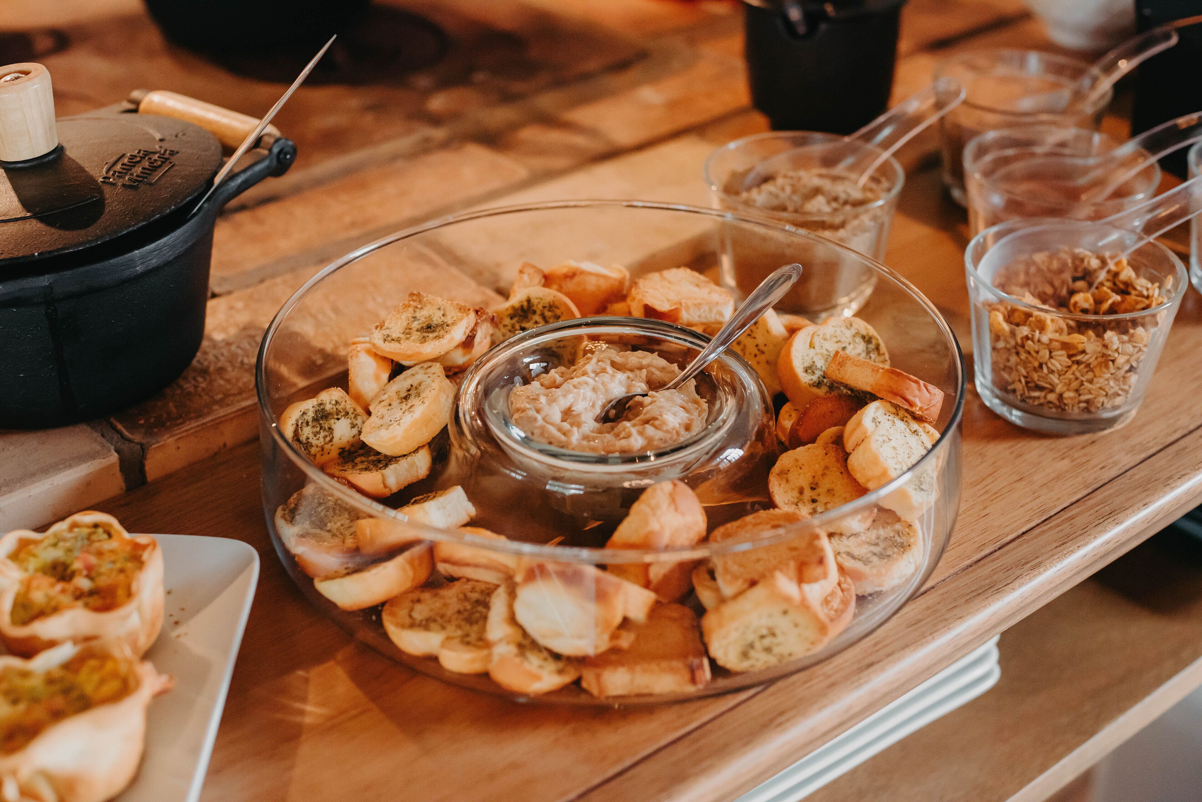 Ein Buffet mit verschiedenen Speisen, darunter Brot, Dips und ein Eintopf.