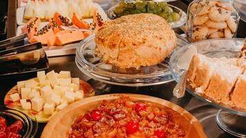 Una mesa de bufé con diversos alimentos, entre ellos queso, frutas y repostería.