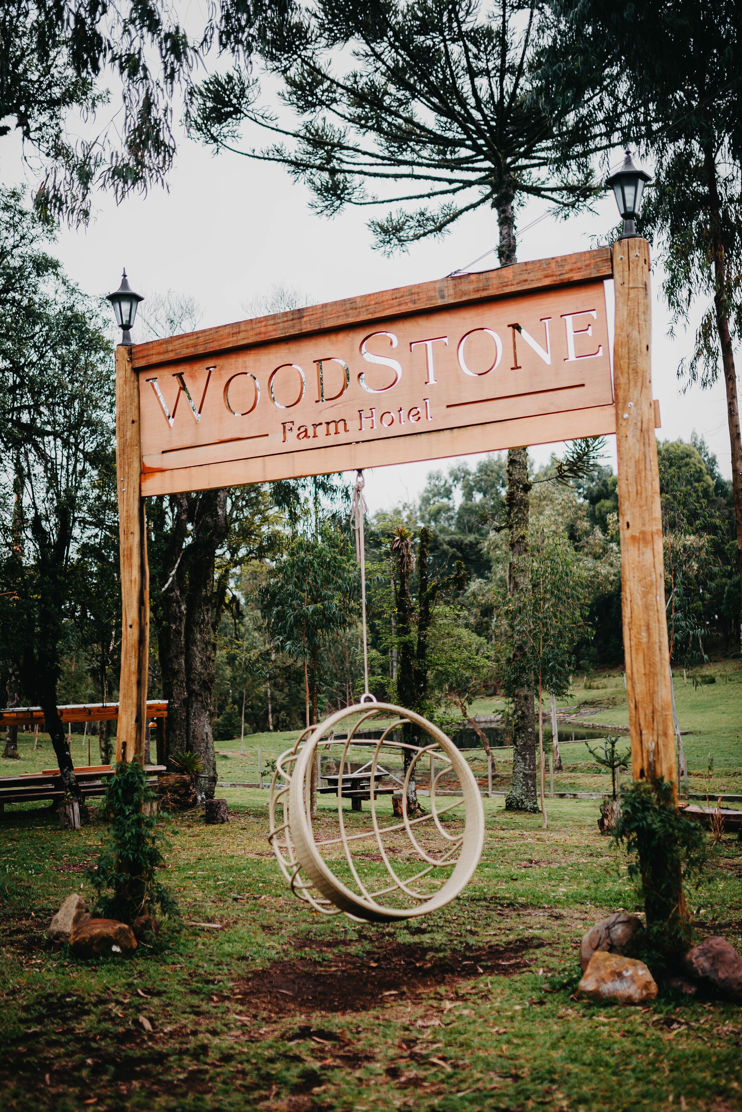 Señal de madera del Hotel Woodstone Farm con un columpio debajo.