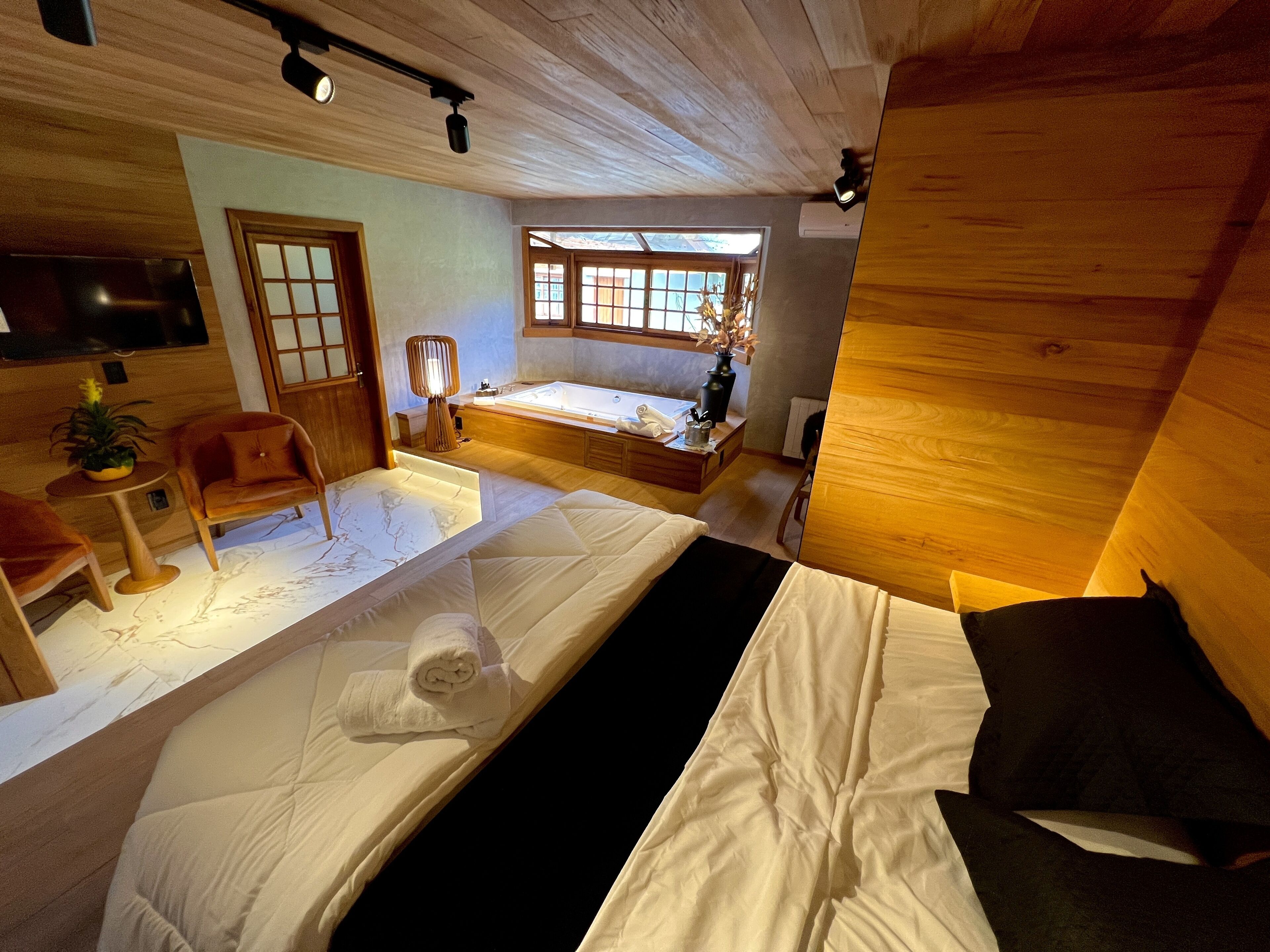 A modern bedroom with a large bed, a sofa, a small table, and a TV.
