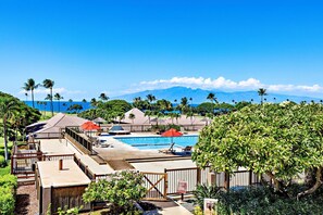Ett semesterhotell med en swimmingpool, solstolar och utsikt över havet och bergen.
