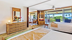 A hotel room with two beds, a large mirror, a dresser, and a balcony with a view of the ocean.