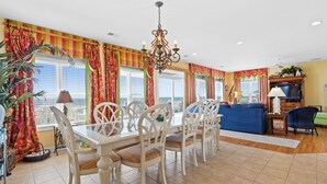 A dining area with a table and chairs, a chandelier, and a view of the ocean. - Oceanfront Luxury Home with Incredible Panaramic Views & Elevator (Ocean Isle Beach)