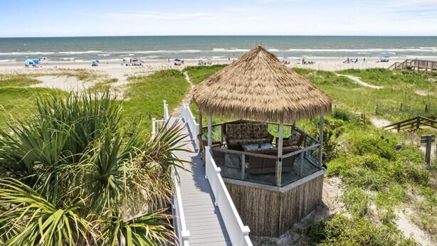A beach view with a thatched-roof gazebo and a wooden deck. - Oceanfront Luxury Home with Incredible Panaramic Views & Elevator (Ocean Isle Beach)