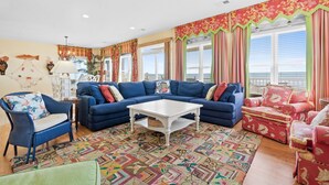 A living room with a blue sofa, a white coffee table, and a patterned rug. - Oceanfront Luxury Home with Incredible Panaramic Views & Elevator (Ocean Isle Beach)