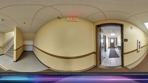 A hallway with an exit sign, a staircase, and a door leading to another room. - Ambridge Inn (Ambridge)