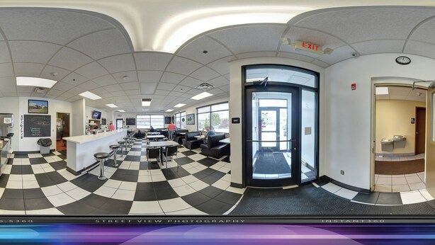 A lobby with a checkered floor, a reception desk, seating area, and an exit door. - Ambridge Inn (Ambridge)