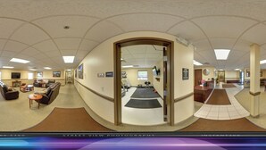 A panoramic view of a hotel lobby with a reception desk, seating area, and exercise equipment. - Ambridge Inn (Ambridge)