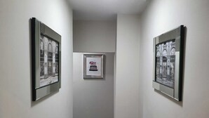 A hallway with framed pictures on the walls, a framed artwork on the wall, and a carpeted floor. - Immaculate 3-bed Studio in Liverpool City Centre (Liverpool)
