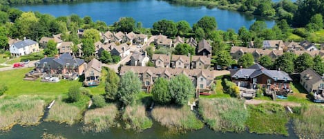 Vista aérea de una zona residencial con casas agrupadas alrededor de un lago, rodeado de vegetación.