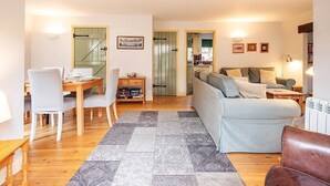 A living room with a sofa, a dining table with chairs, a coffee table, and a rug. - Mill Village 59, Millstream Cottage (P) - On-site Facilities, Pool, Sleeps 6 (Somerford Keynes)