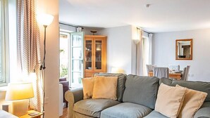 A cozy living room with a grey sofa, wooden flooring, and a dining area in the background. - Mill Village 59, Millstream Cottage (P) - On-site Facilities, Pool, Sleeps 6 (Somerford Keynes)