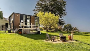 Una casa moderna con terraza, mobiliario exterior y un árbol grande.