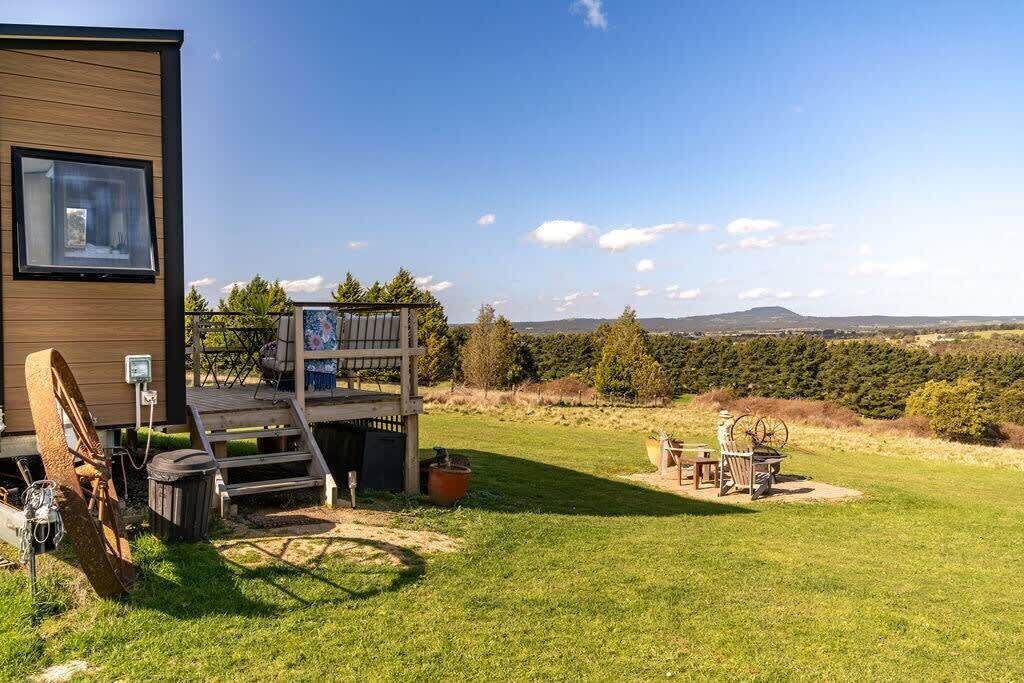Un bâtiment moderne doté d’une terrasse, offrant une vue sur la campagne et aménagé avec du mobilier d’extérieur.
