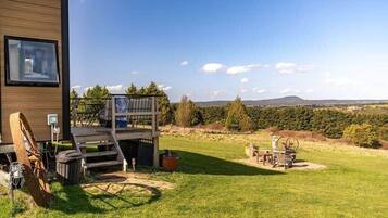 Un bâtiment moderne doté d’une terrasse, offrant une vue sur la campagne et aménagé avec du mobilier d’extérieur.