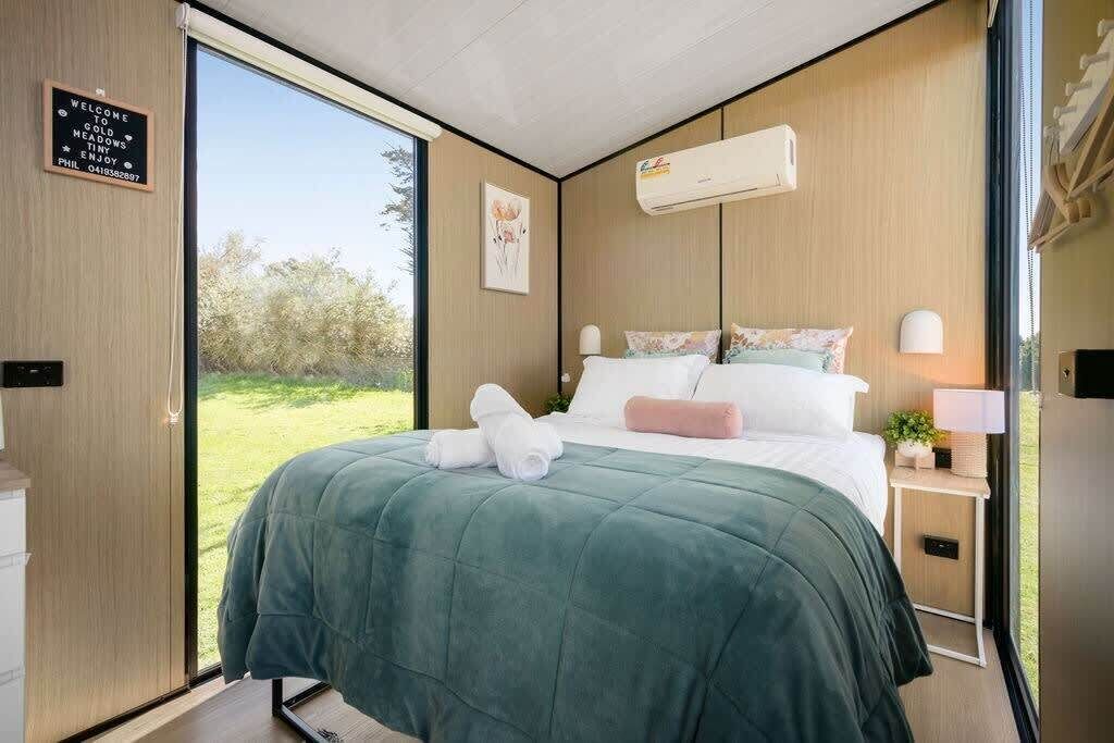 Une chambre à coucher moderne, dotée d’un grand lit, d’une table de chevet avec une lampe et offrant une vue sur l’extérieur.