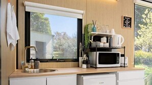 Una cocina compacta equipada con microondas integrado, un lavamanos y un refrigerador pequeño.