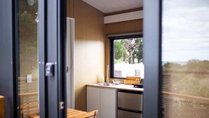 A compact kitchen with a window, a sink, and a wooden table. - Pacific View by Tiny Away (Leithfield)