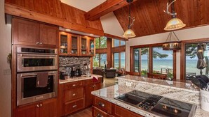 A kitchen with wooden cabinets, a built-in oven, a granite countertop, and a view of the ocean. - Lake Superior Cabin, 4BR, Sleeps 10, Private Beach (Paradise)