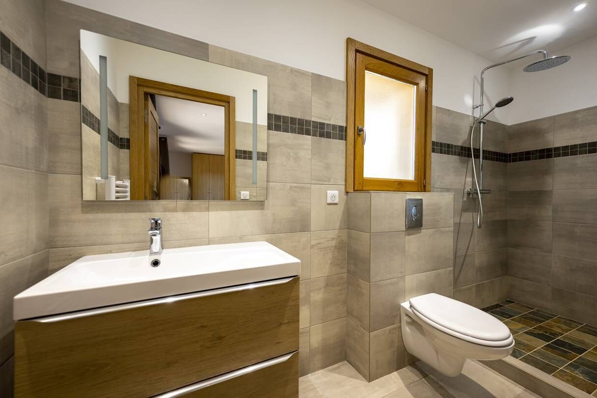 Une salle de bain moderne avec un lavabo blanc, un meuble en bois et un espace douche.