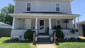 A two-story house with a front porch, a mailbox, and a small garden.