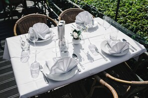 Mesa para cuatro personas, con mantel blanco, copas y cubiertos.