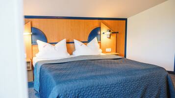 A hotel room with a large bed, wooden headboard, and two bedside lamps.