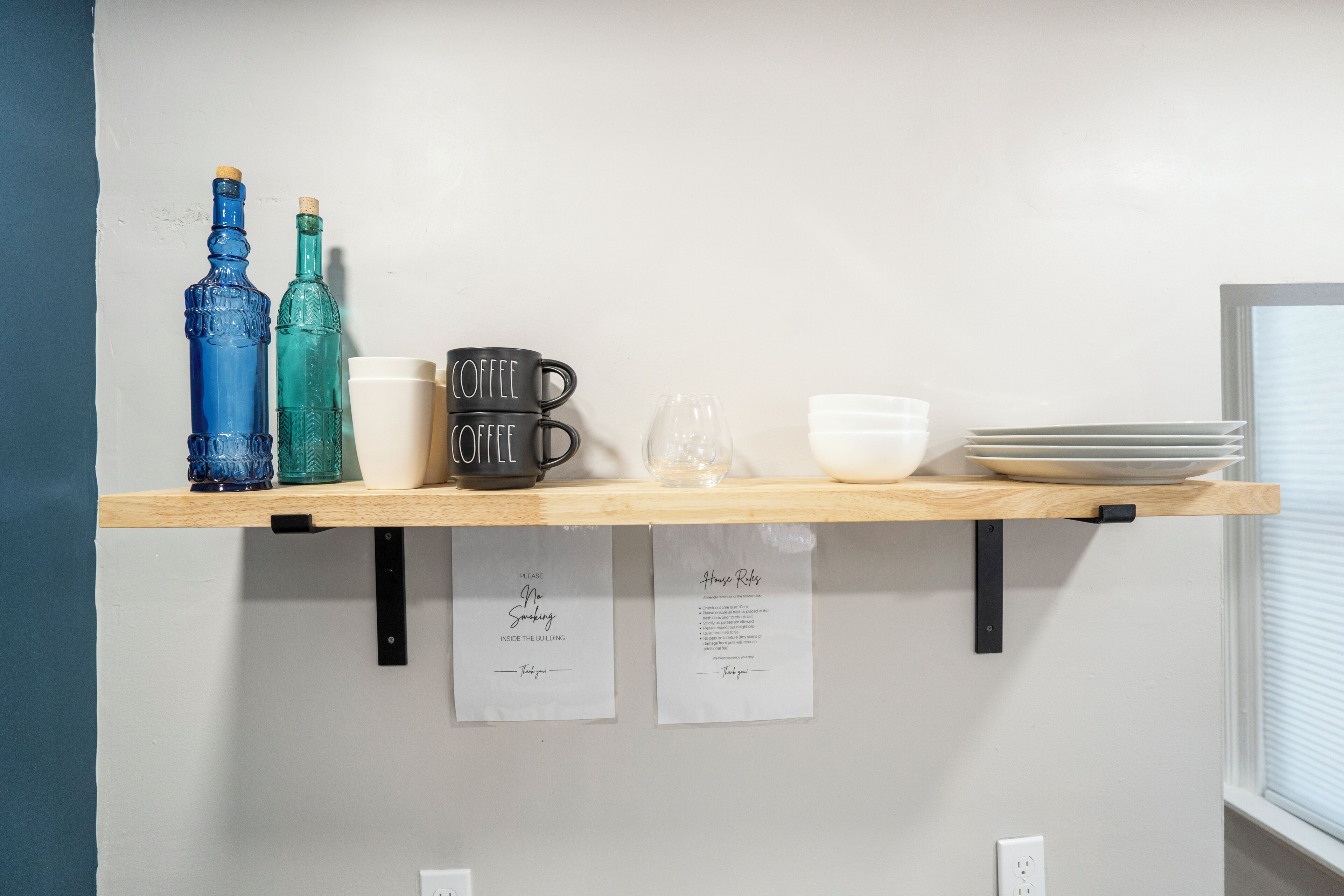 Une étagère contenant divers objets, notamment des bouteilles, des tasses à café et des assiettes.