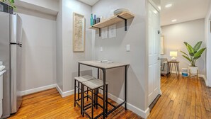 A modern kitchen with a built-in refrigerator, a wooden table with stools, and a shelf with kitchenware. - Cozy, dog-friendly, downtown (Frederick)