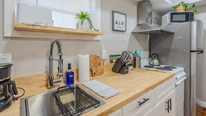 A modern kitchen with a wooden countertop, stainless steel appliances, a built-in microwave, and a window with blinds. - Cozy, dog-friendly, downtown (Frederick)