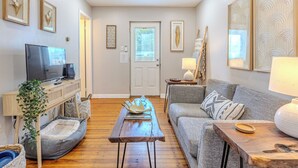 A cozy living room with a TV, sofa, coffee table, and decorative items. - Cozy, dog-friendly, downtown (Frederick)