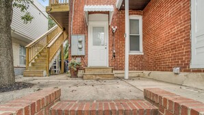 A brick house with a white door, a wooden staircase, and a small porch area. - Cozy, dog-friendly, downtown (Frederick)