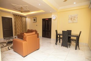Ein Wohnzimmer mit einer Couch, einem Esstisch mit Stühlen, einem Deckenventilator und einer Uhr an der Wand.