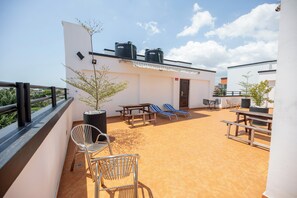 Eine Dachterrasse mit Sitzgelegenheiten im Freien, einem Topfpflanzen und Wassertanks.