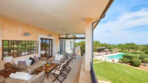 Un espace extérieur aménagé avec des meubles en osier, une piscine et une vue sur le paysage.