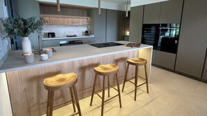 Une cuisine moderne dotée d’un îlot central, de tabourets de bar, de meubles en bois et de luminaires suspendus.