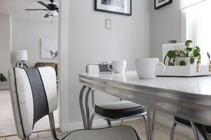 Een eetruimte met een ronde tafel, stoelen en een potplant.