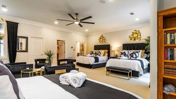 A hotel room with two beds, a ceiling fan, a bookshelf, and a large mirror.