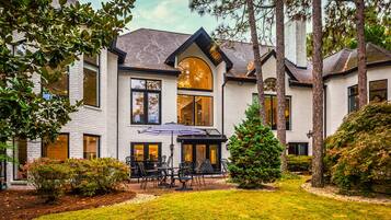 Une maison moderne dotée d’un patio comprenant un espace salon extérieur et une grande fenêtre donnant sur la cour.