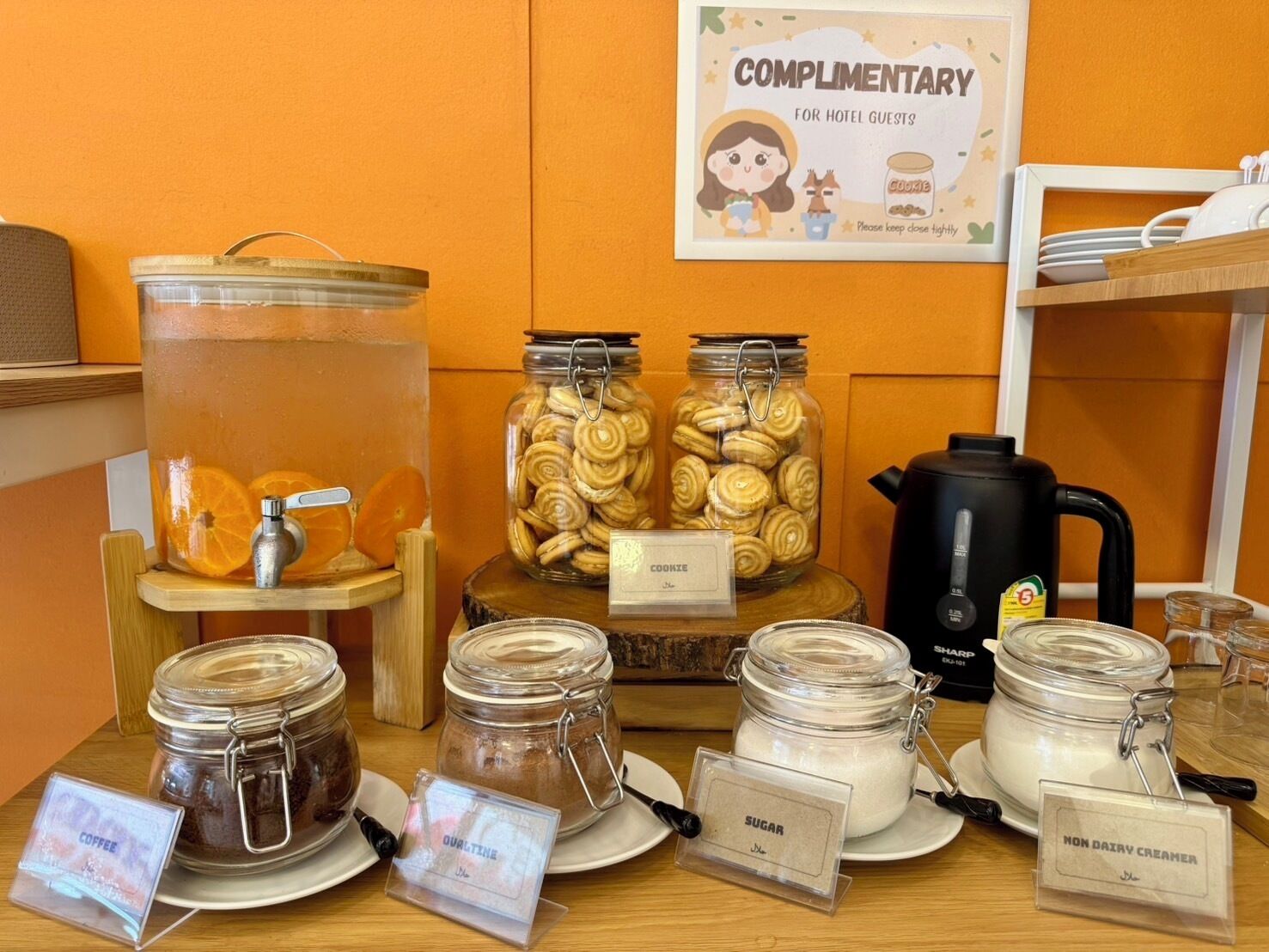 A complimentary station for hotel guests with jars of cookies, sugar, coffee, and other items.