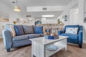 A modern living room with a grey sectional sofa, a blue armchair, and a white coffee table with a woven basket.